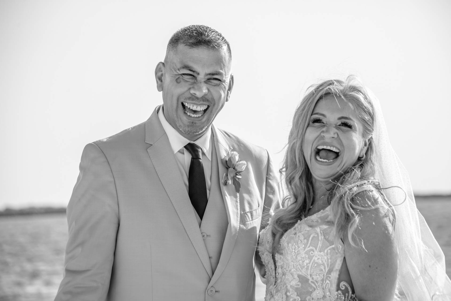 bride and groom laughing on the beach
