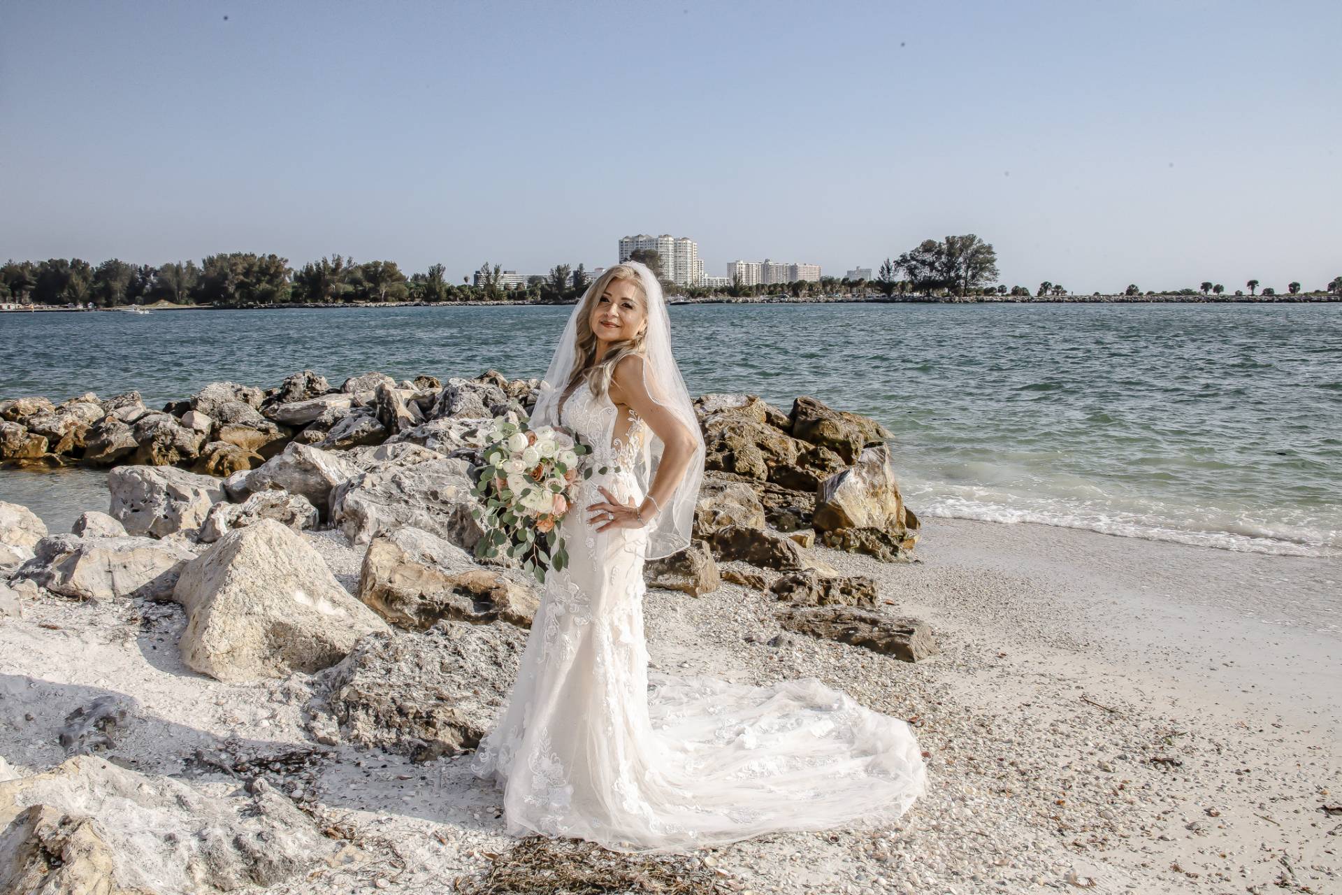 bride standing by some rocks on the beach